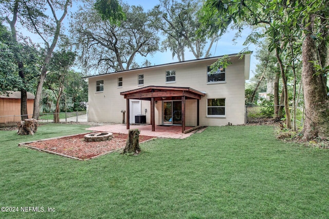 rear view of house with central AC unit, a fire pit, a yard, and a patio area