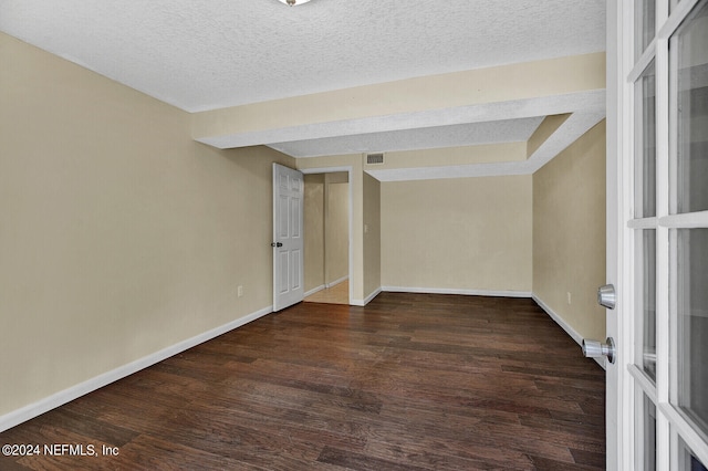 unfurnished room with a textured ceiling and dark wood-type flooring