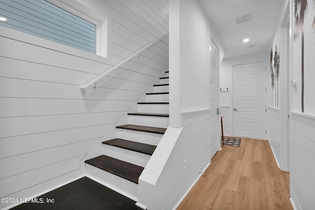 stairs with wooden walls and hardwood / wood-style floors