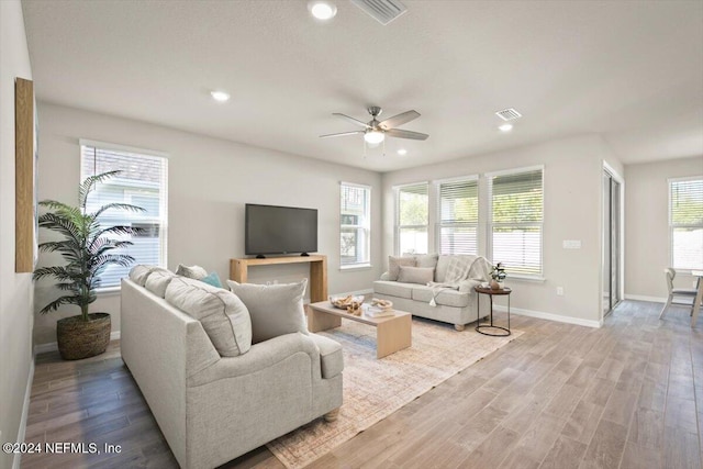 living room with a wealth of natural light, light hardwood / wood-style flooring, and ceiling fan