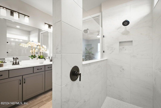 bathroom featuring vanity, a tile shower, hardwood / wood-style flooring, and ceiling fan