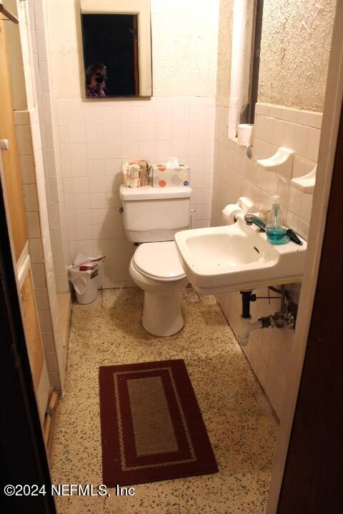 bathroom featuring tile walls, toilet, and sink