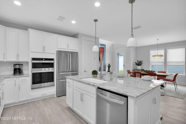 kitchen with an island with sink, sink, stainless steel appliances, and white cabinets