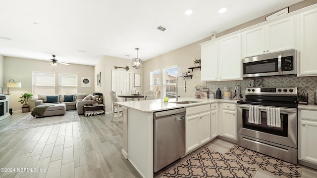 kitchen with white cabinetry, kitchen peninsula, appliances with stainless steel finishes, and sink