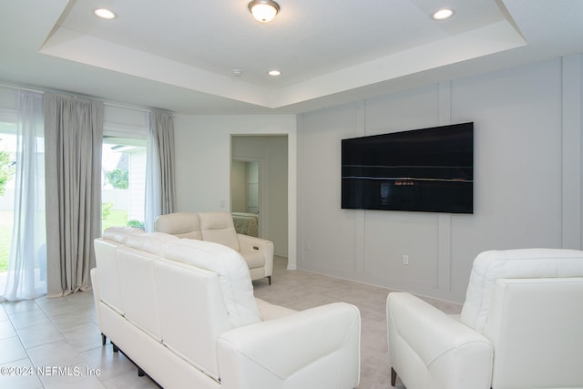 living room with a tray ceiling and light tile patterned floors