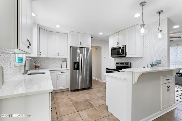 kitchen featuring appliances with stainless steel finishes, white cabinetry, sink, and hanging light fixtures