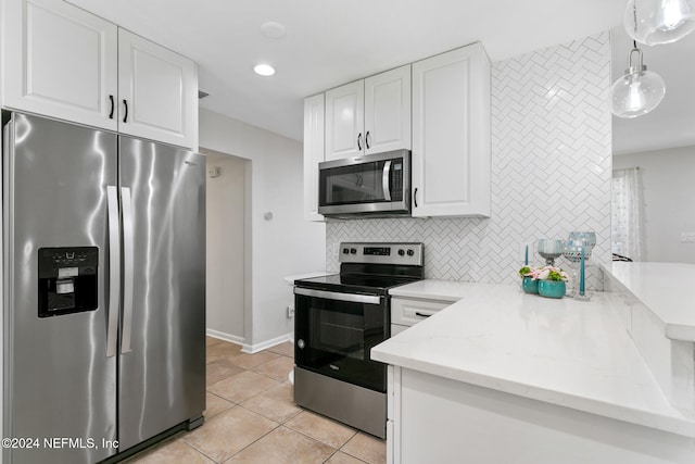 kitchen featuring hanging light fixtures, stainless steel appliances, light stone countertops, light tile patterned floors, and white cabinetry