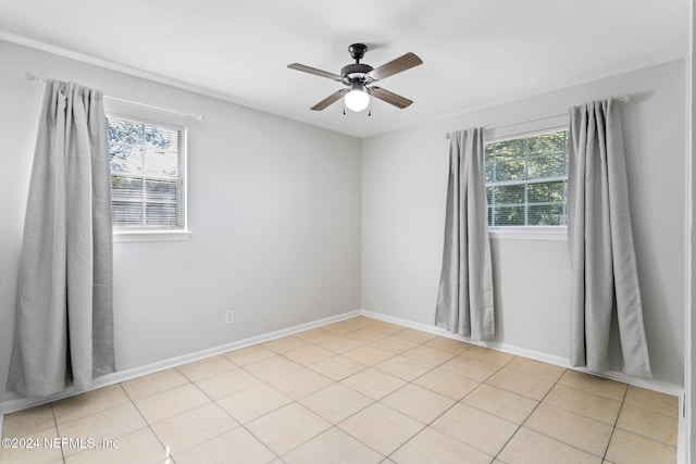 spare room with light tile patterned floors, plenty of natural light, and ceiling fan