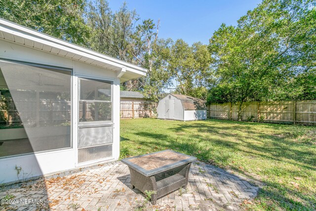 view of yard featuring a shed, a patio area, and a sunroom