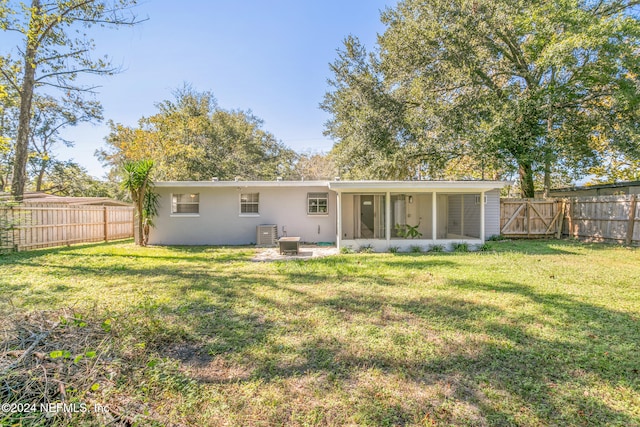 rear view of property featuring a sunroom, central AC, and a lawn