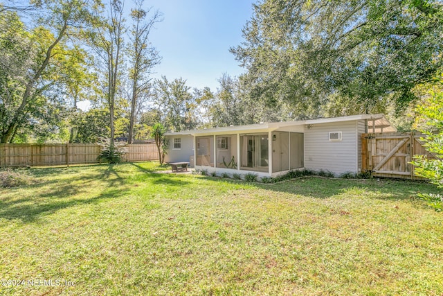 back of property featuring a sunroom and a lawn