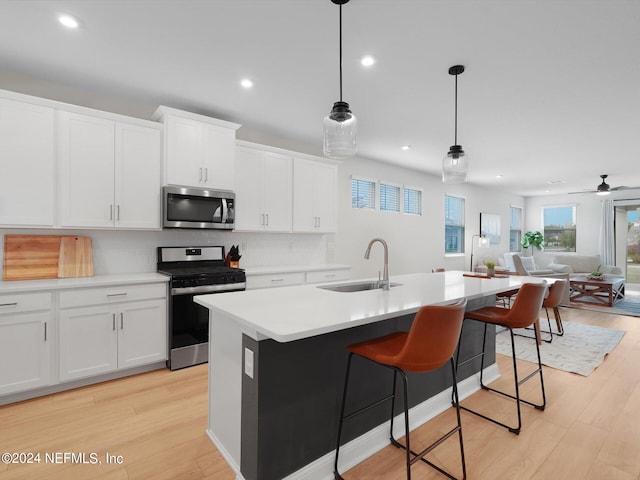 kitchen with a center island with sink, sink, stainless steel appliances, and light hardwood / wood-style floors