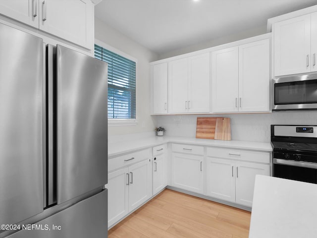 kitchen with decorative backsplash, appliances with stainless steel finishes, light wood-type flooring, and white cabinetry