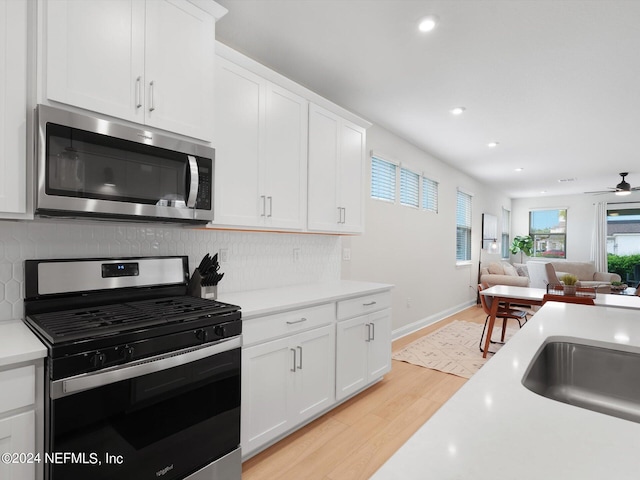 kitchen with white cabinetry, stainless steel appliances, light hardwood / wood-style floors, and tasteful backsplash