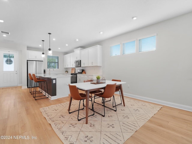 dining area with sink, light hardwood / wood-style flooring, and a wealth of natural light