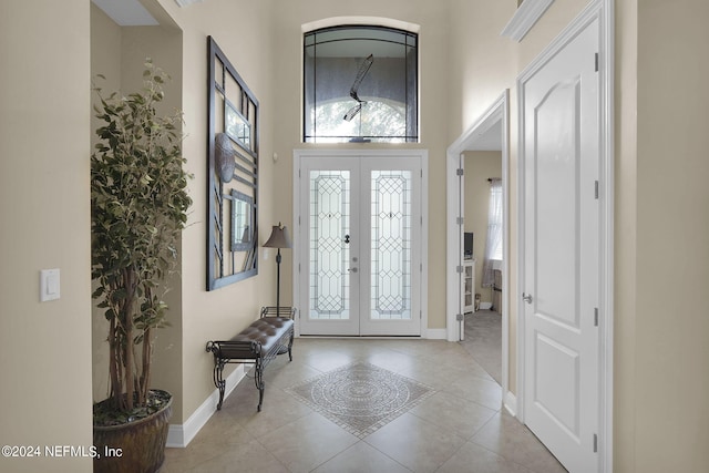 entryway featuring a high ceiling, light tile patterned floors, and french doors