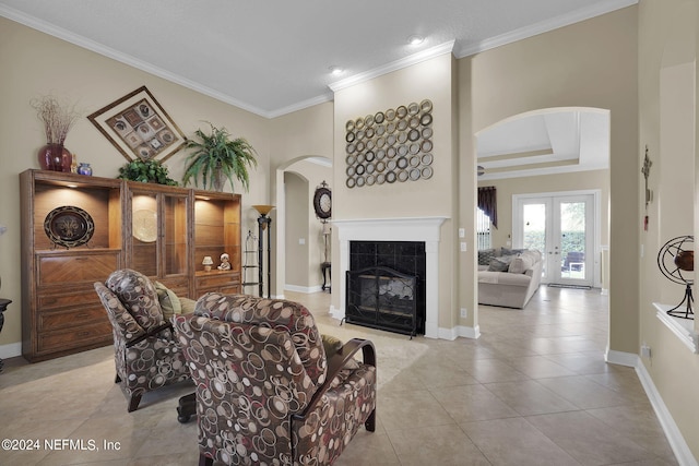 living room featuring ornamental molding, a tiled fireplace, light tile patterned floors, and french doors