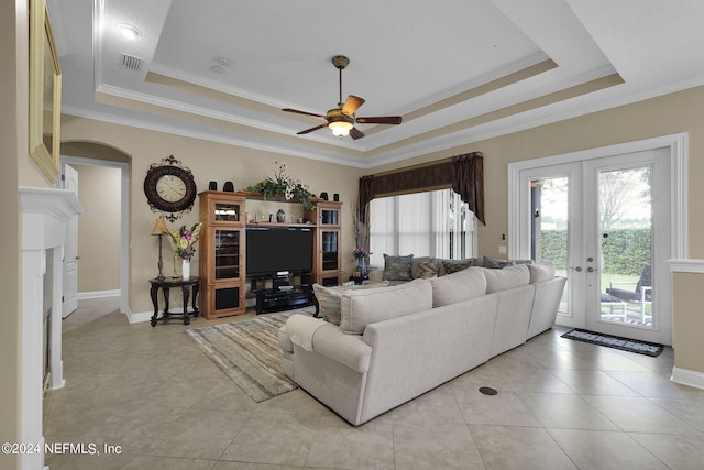 living room with ceiling fan, a tray ceiling, crown molding, and french doors