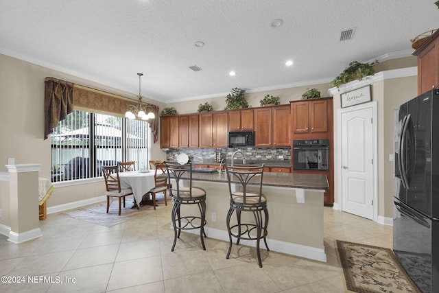 kitchen with pendant lighting, a kitchen island with sink, a kitchen breakfast bar, black appliances, and ornamental molding