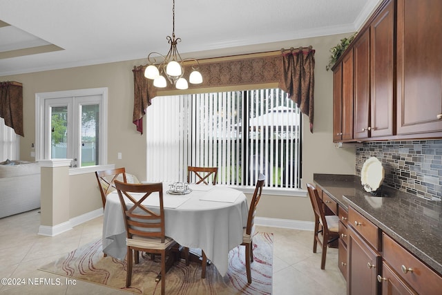 tiled dining room with crown molding and an inviting chandelier