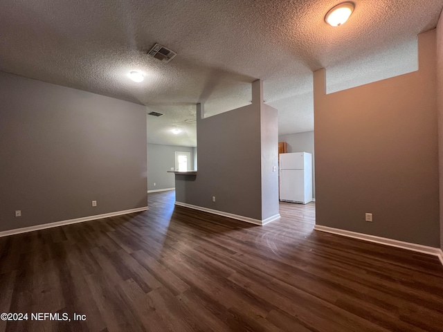 empty room with a textured ceiling and dark hardwood / wood-style flooring