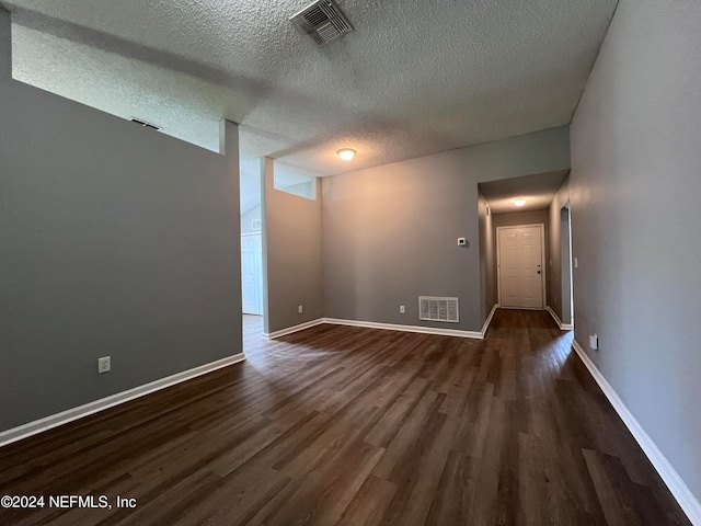 unfurnished room with a textured ceiling and dark hardwood / wood-style floors