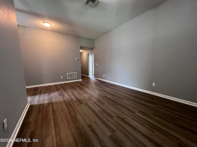 spare room with a textured ceiling and dark hardwood / wood-style flooring