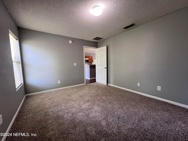 carpeted empty room featuring a textured ceiling