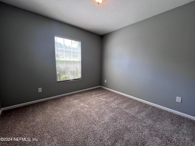 carpeted empty room with a textured ceiling