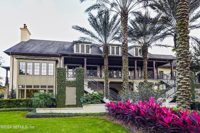 back of property featuring a lawn and a balcony