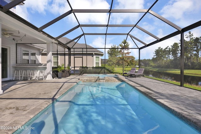 view of swimming pool with glass enclosure, a water view, ceiling fan, and a patio