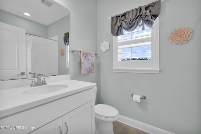 bathroom featuring walk in shower, wood-type flooring, vanity, and toilet