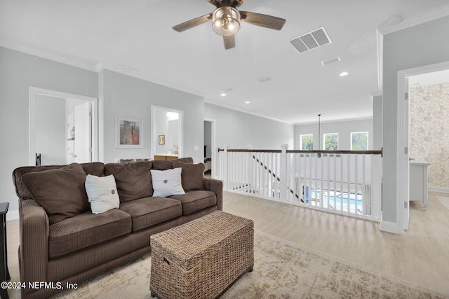 living room with light hardwood / wood-style flooring, ceiling fan with notable chandelier, and crown molding