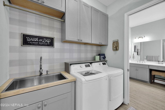 laundry room featuring cabinets, light hardwood / wood-style floors, independent washer and dryer, and sink