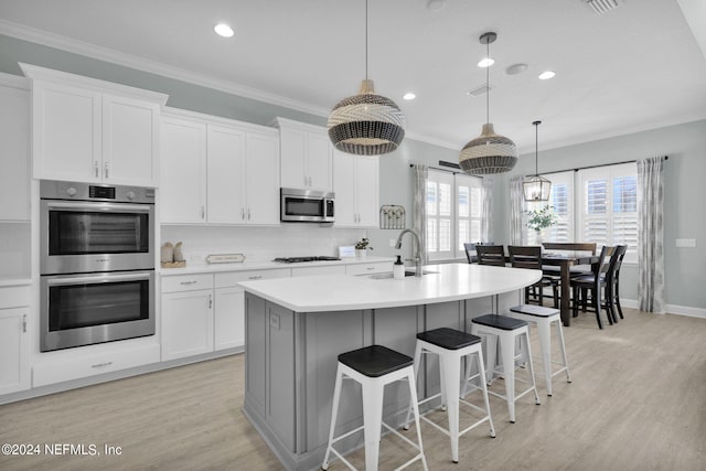 kitchen featuring an island with sink, appliances with stainless steel finishes, sink, and white cabinetry