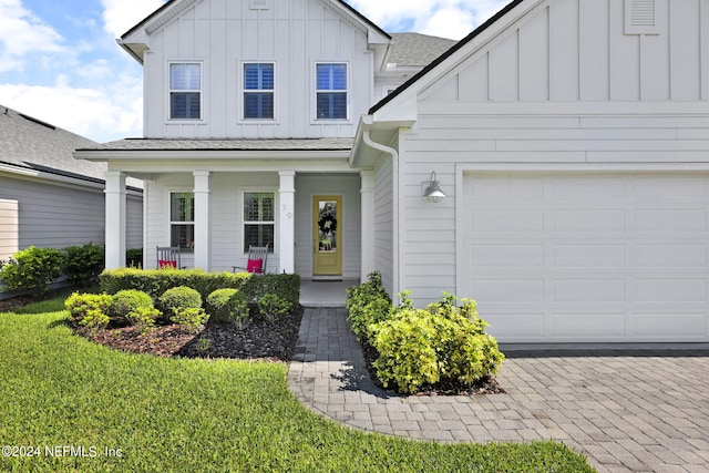 view of front of house featuring a front yard, a porch, and a garage