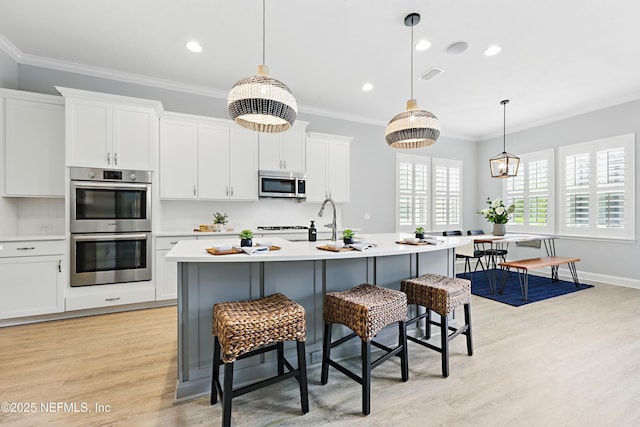 79 Shadow Ridge Trl, Ponte Vedra, FL 32081 - kitchen featuring a breakfast bar area, light wood finished floors, light countertops, appliances with stainless steel finishes, and visible vents