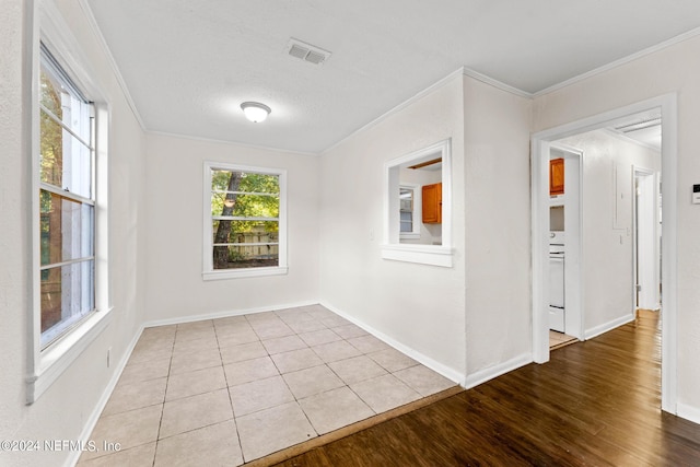 empty room with a textured ceiling, crown molding, and light hardwood / wood-style floors