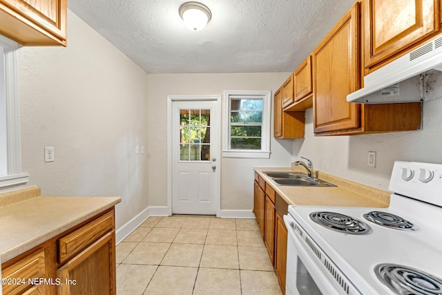 kitchen with a textured ceiling, white electric range oven, light tile patterned floors, and sink