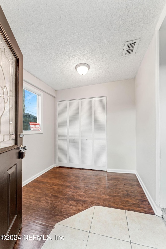 unfurnished bedroom featuring wood-type flooring, a textured ceiling, and a closet