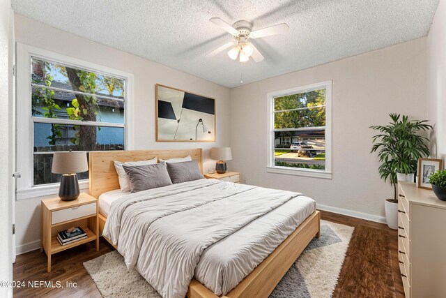 bedroom with ceiling fan, dark wood-type flooring, and a textured ceiling