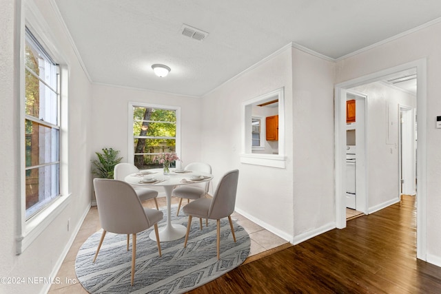 dining area featuring ornamental molding, wood-type flooring, and a textured ceiling