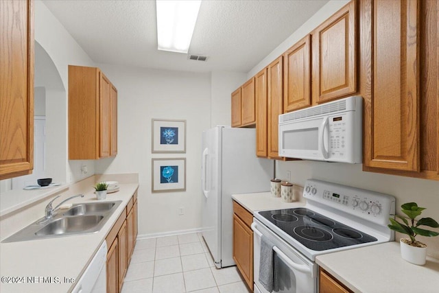 kitchen featuring white appliances, a textured ceiling, light tile patterned flooring, and sink