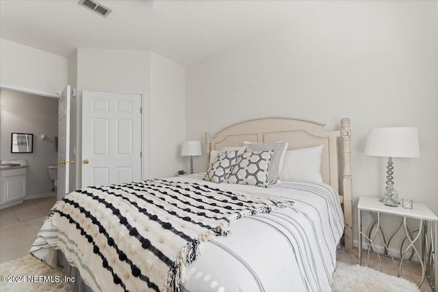 bedroom featuring ensuite bath and light carpet