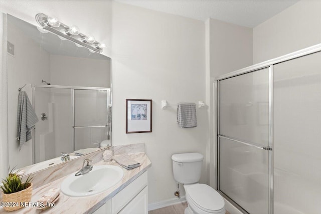 bathroom with walk in shower, vanity, and toilet