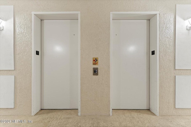 corridor with elevator and light colored carpet