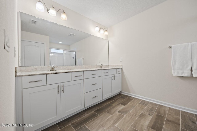 bathroom with an enclosed shower, vanity, and a textured ceiling