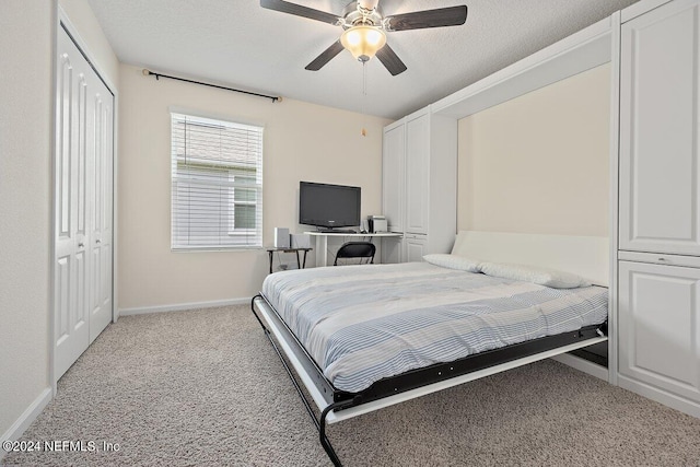 carpeted bedroom featuring ceiling fan and a textured ceiling