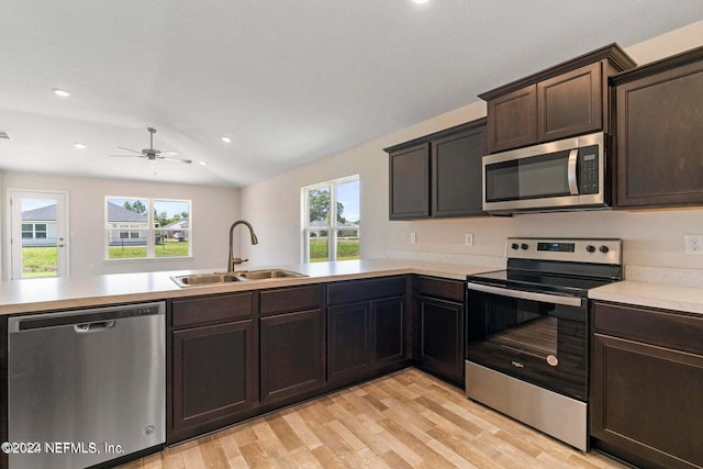 kitchen featuring light countertops, appliances with stainless steel finishes, a sink, dark brown cabinetry, and a peninsula