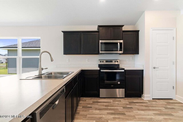 kitchen featuring light wood finished floors, appliances with stainless steel finishes, light countertops, and a sink